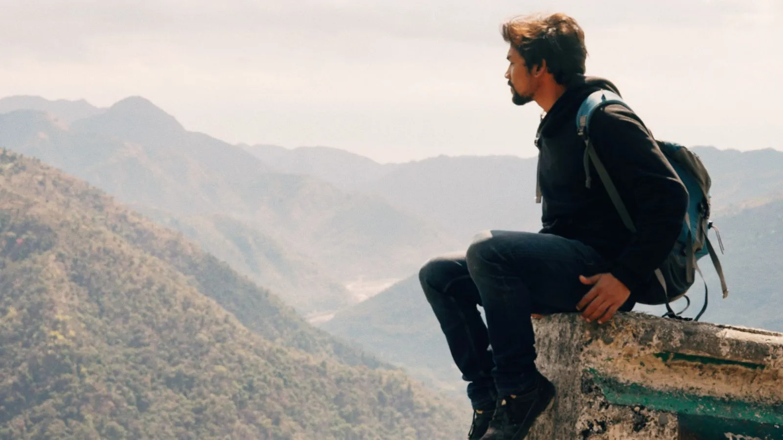 شاب مسافر يستمتع بالمناظر الجبلية ضمن رحلته إلى إحدى دول يمكن للعرب زيارتها بدون فيزا.